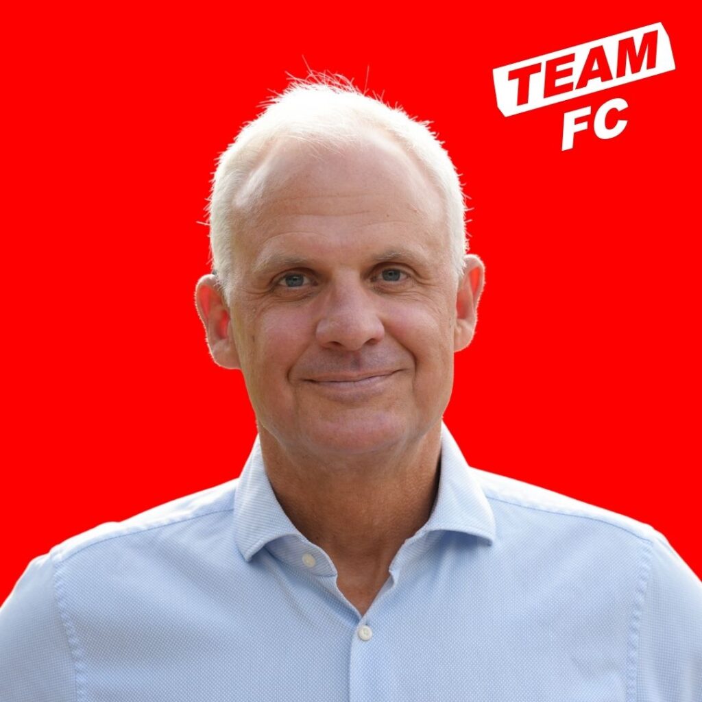 Porträt von Dr. Jörg Alvermann, Kandidat Team FC, vor rotem Hintergrund.